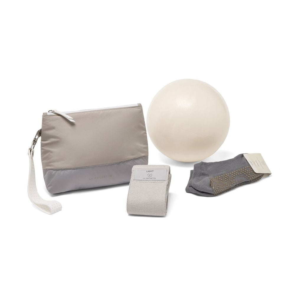 Yoga accessories including a grey pouch, white pilates ball, and grey grip socks and a grey resistance band