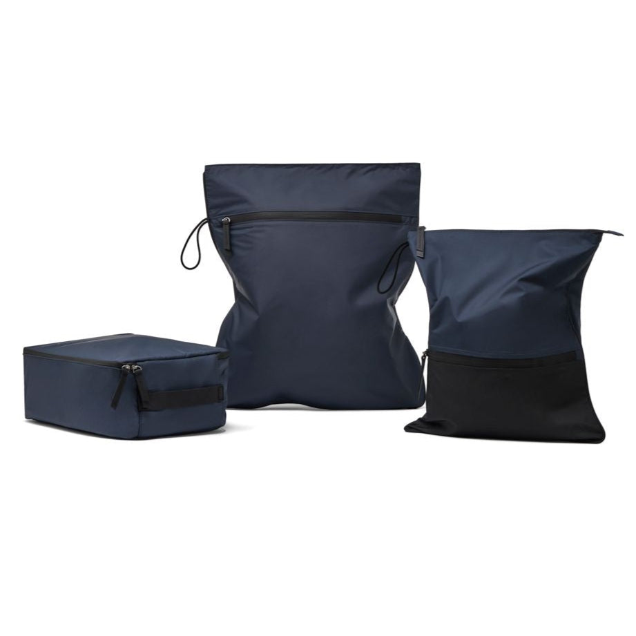 Three-piece workout bag bundle, including a structured navy shoe bag, a larger navy waterproof kit bag, and a two-tone black and navy sweat bag, designed for organised gym and travel storage.