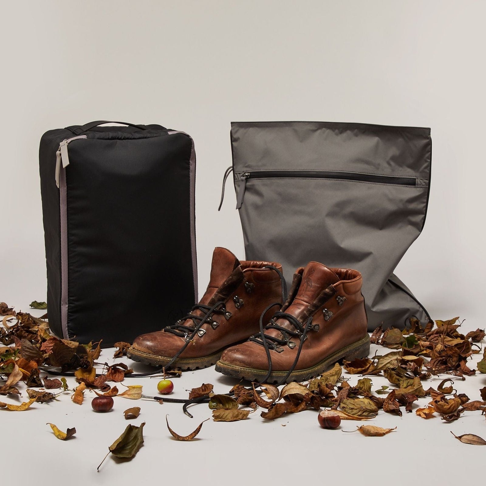 Large black and grey Shoe Carry with Kit Bag in the same colourway. A pair of walking boots are in front of the bags surrounded by leaves