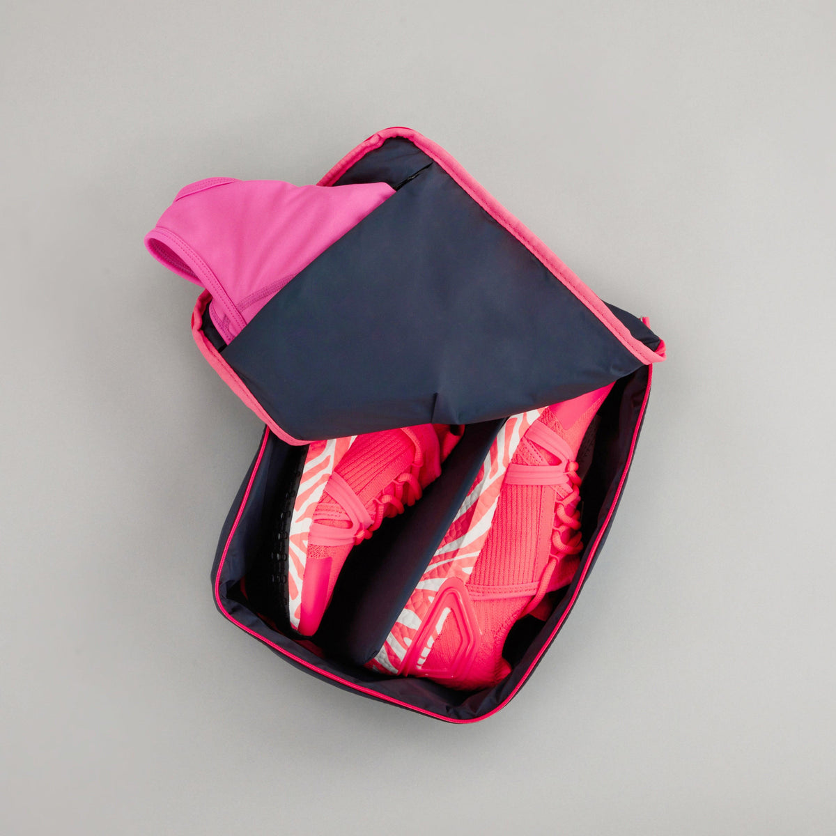 Small Shoe carry in Midnight Neon Pink colourway unzipped showing shoes inside and socks in the inner pocket 