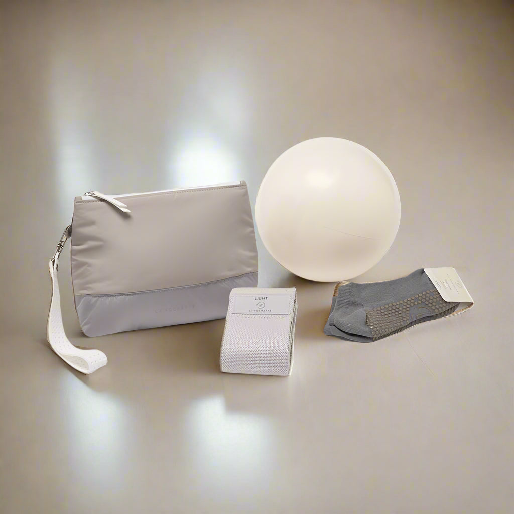 Pilatesaccessories including a pouch, ball, resistance band, and grip socks on a neutral background