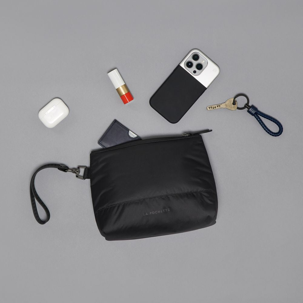 Black pilates 
pouch with phone, keys, and other items on a gray background