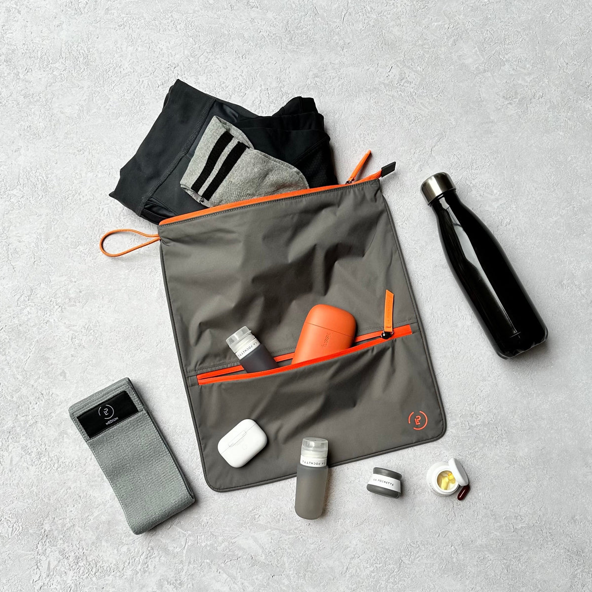 Sweat bag in grey and orange colour with resistance band, travel bottles and water bottle