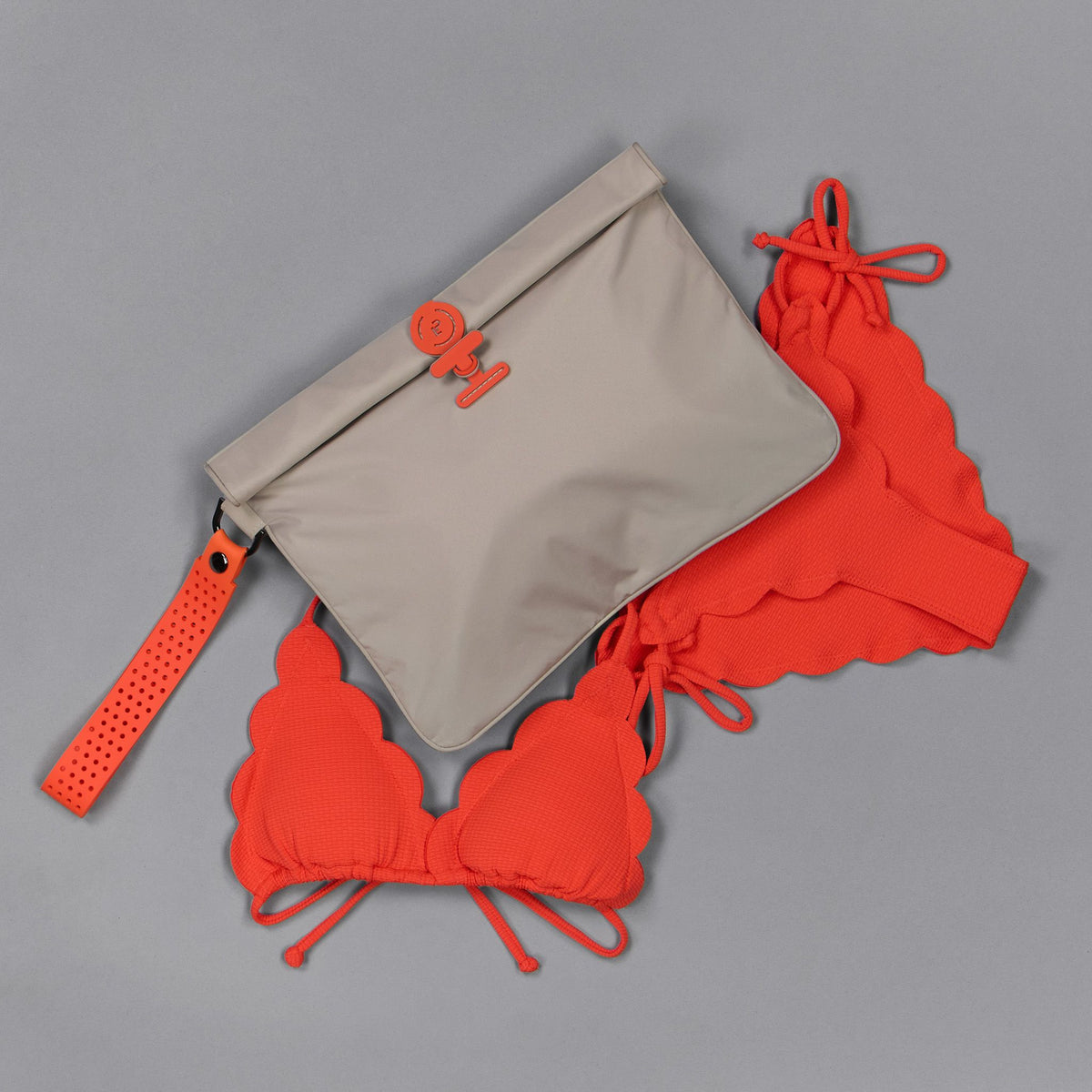 La Pochette Large Waterproof Wet bag in taupe and with red silicone handle and closure shown on grey background with red bikini