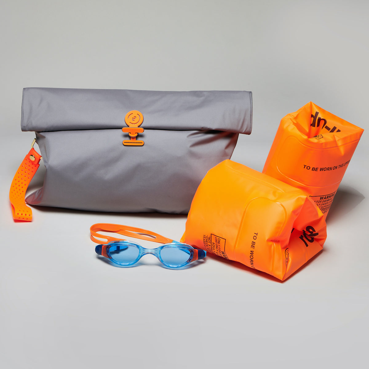 Large Wet Bag in Shadow Neon Orange colourway, folded closed next to arm bands and goggles 
