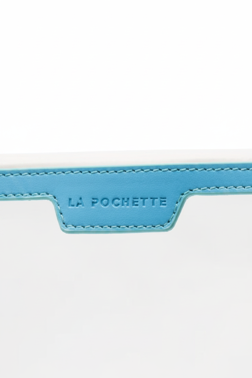 A close-up of a light blue leather strap or trim with 'LA POCHETTE' debossed on the center tab, set against a white background.