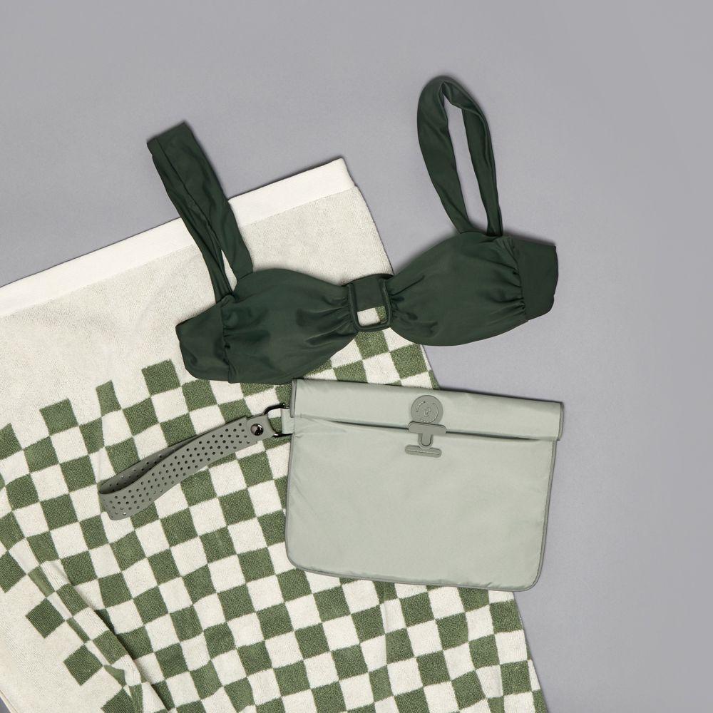 Green bikini top on a checkered towel with a green la pochette wet bag