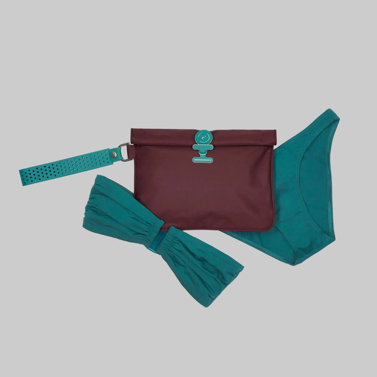Small La Pochette waterproof wet bag in burgundy and silicone teal fastener and detachable handle on white background.