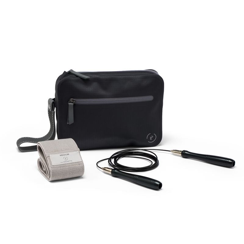 A black La Pochette waterproof aqua  bag with a grey zipper, a grey resistance band and a black-and-silver skipping rope on a clean white background.