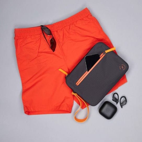 Aqua Bag in black and flame orange.  Shown flat with trunks, and phone in front pocket