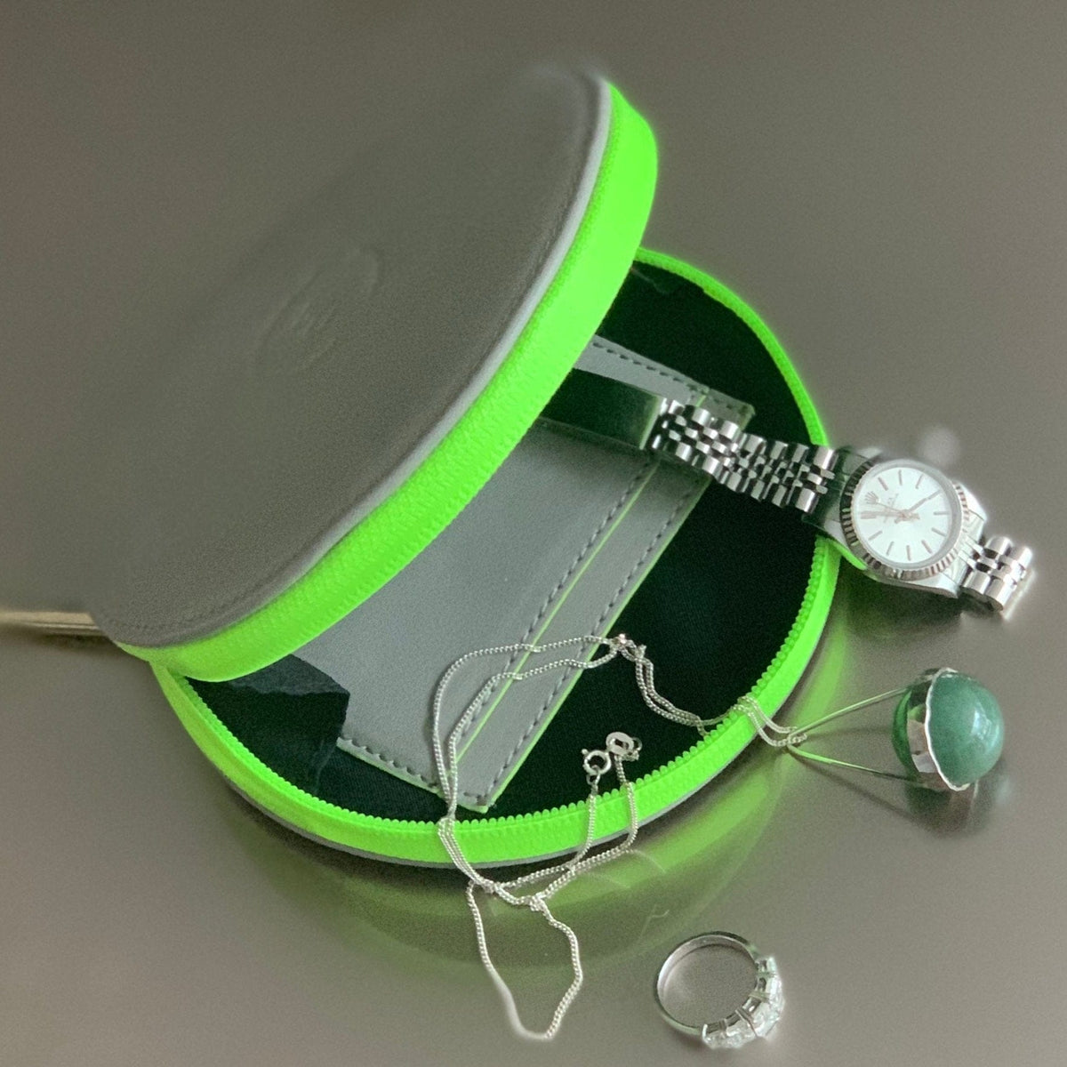 Grey circle purse with neon green trims and various items of jewellery