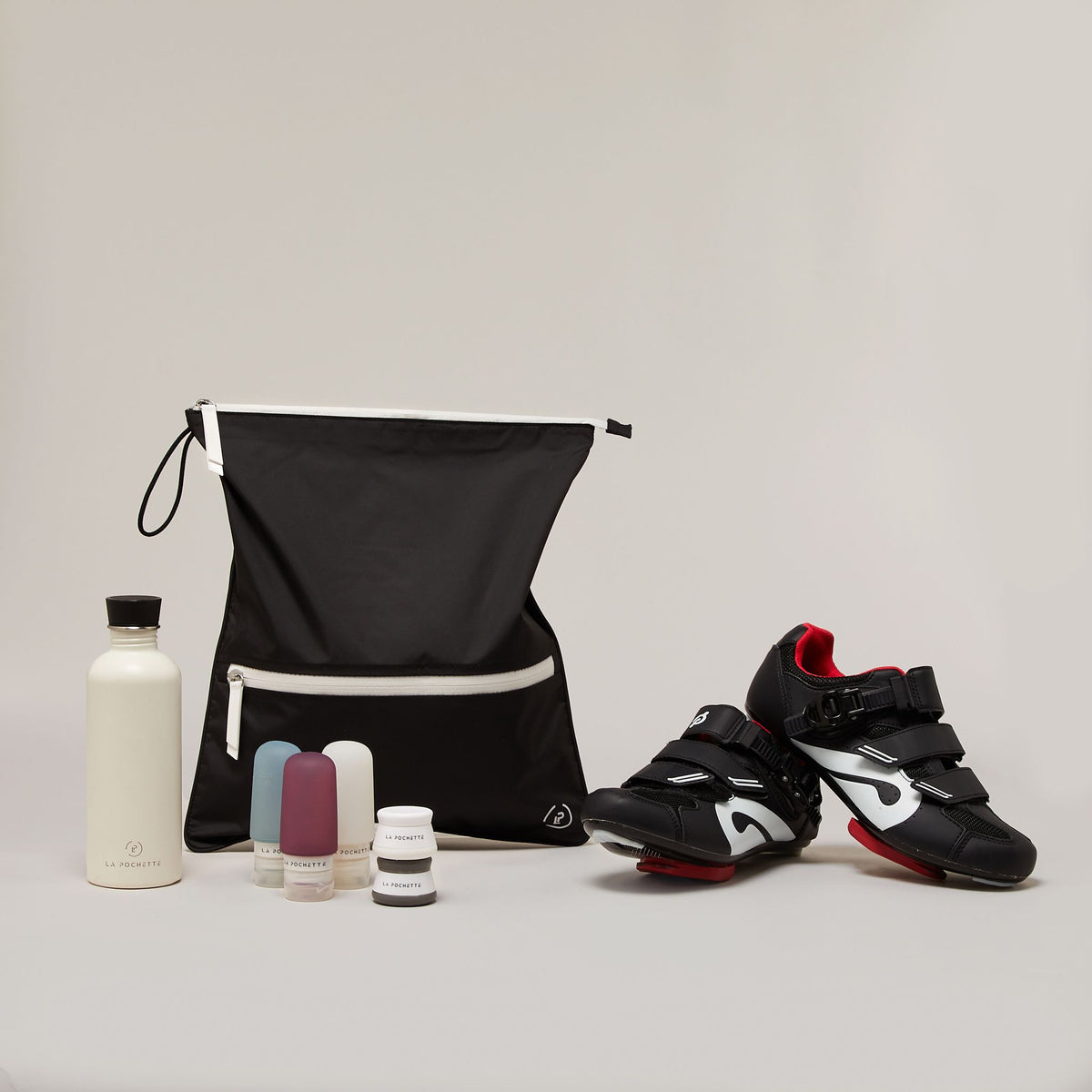 Ink White Sweat Bag with travel pot and bottles shown with a pair of cycling cleats and water bottle