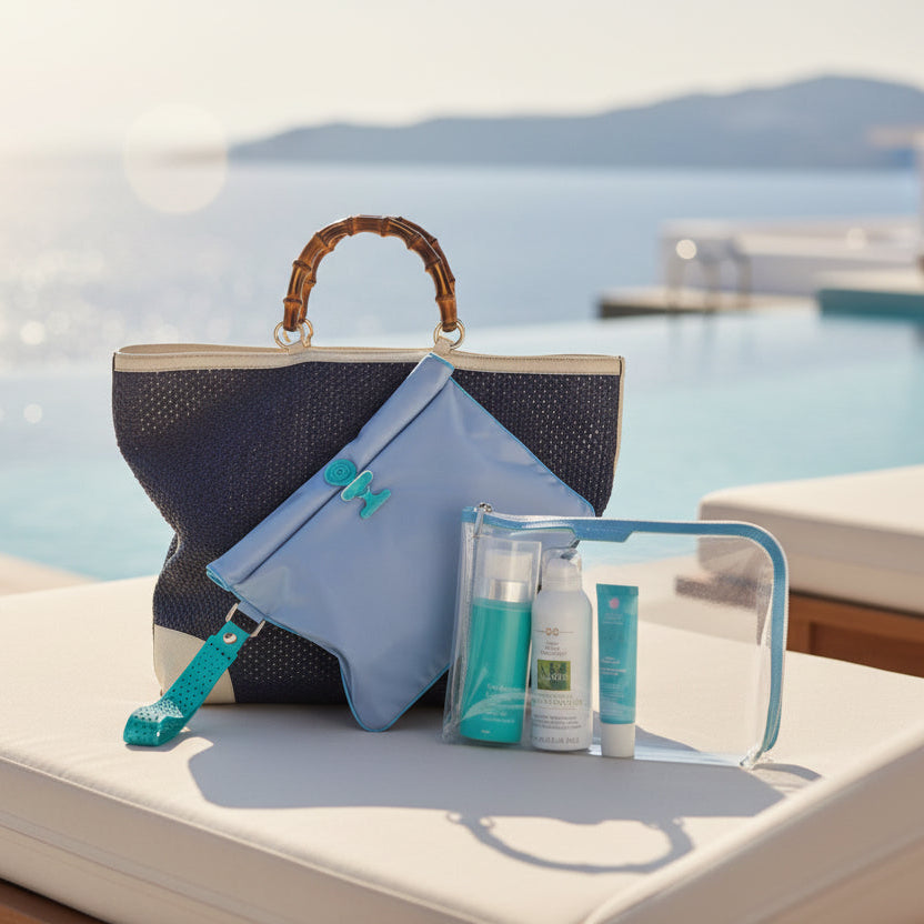 Vivid blue Large waterproof La Pochette Wet Bag shown in front of a navy beach tote and large La Pochette clear pouch with bright blue trims. On a sun lounger with pool and sea backdrop