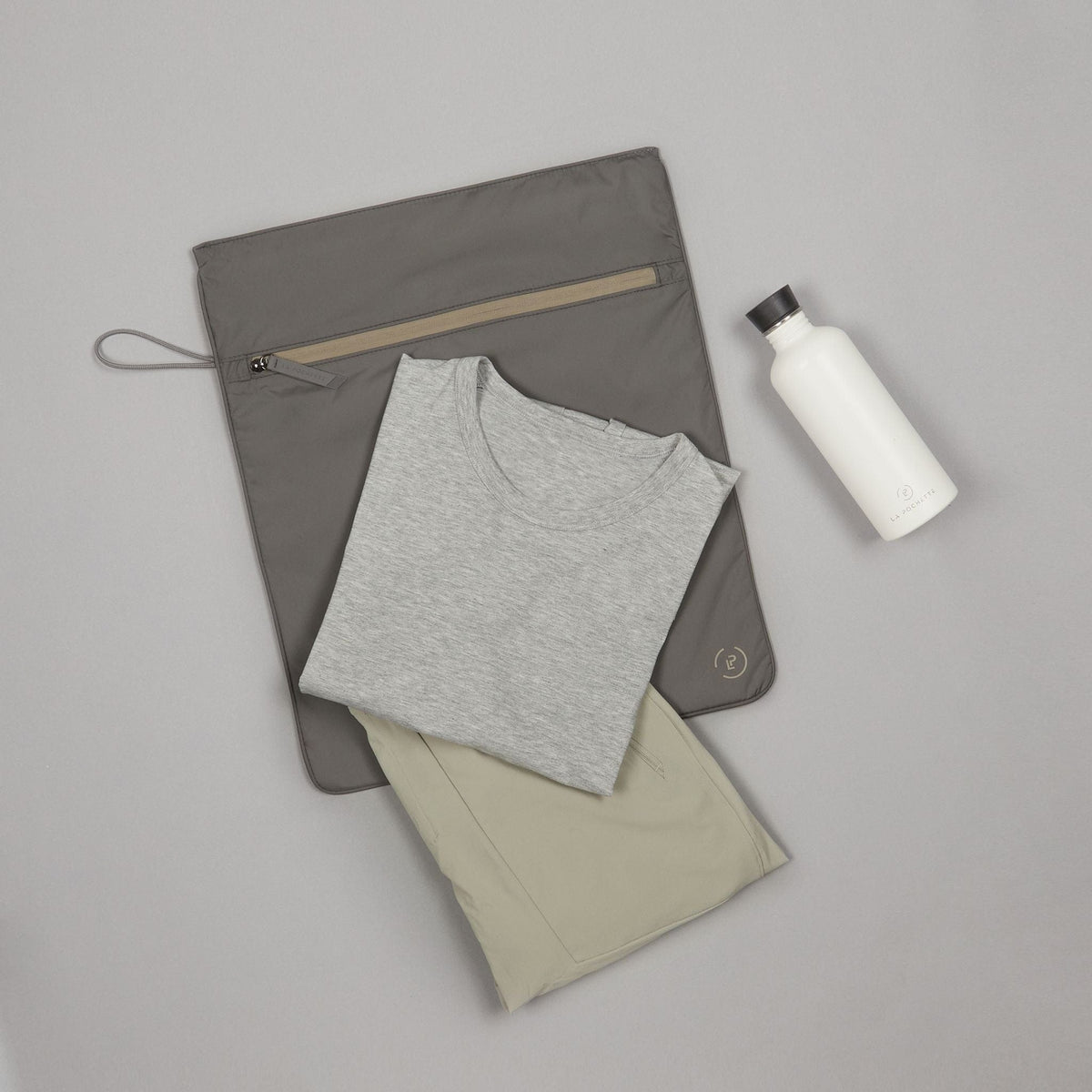 dark grey and beige kit bag styled with folded workout clothes and a water bottle