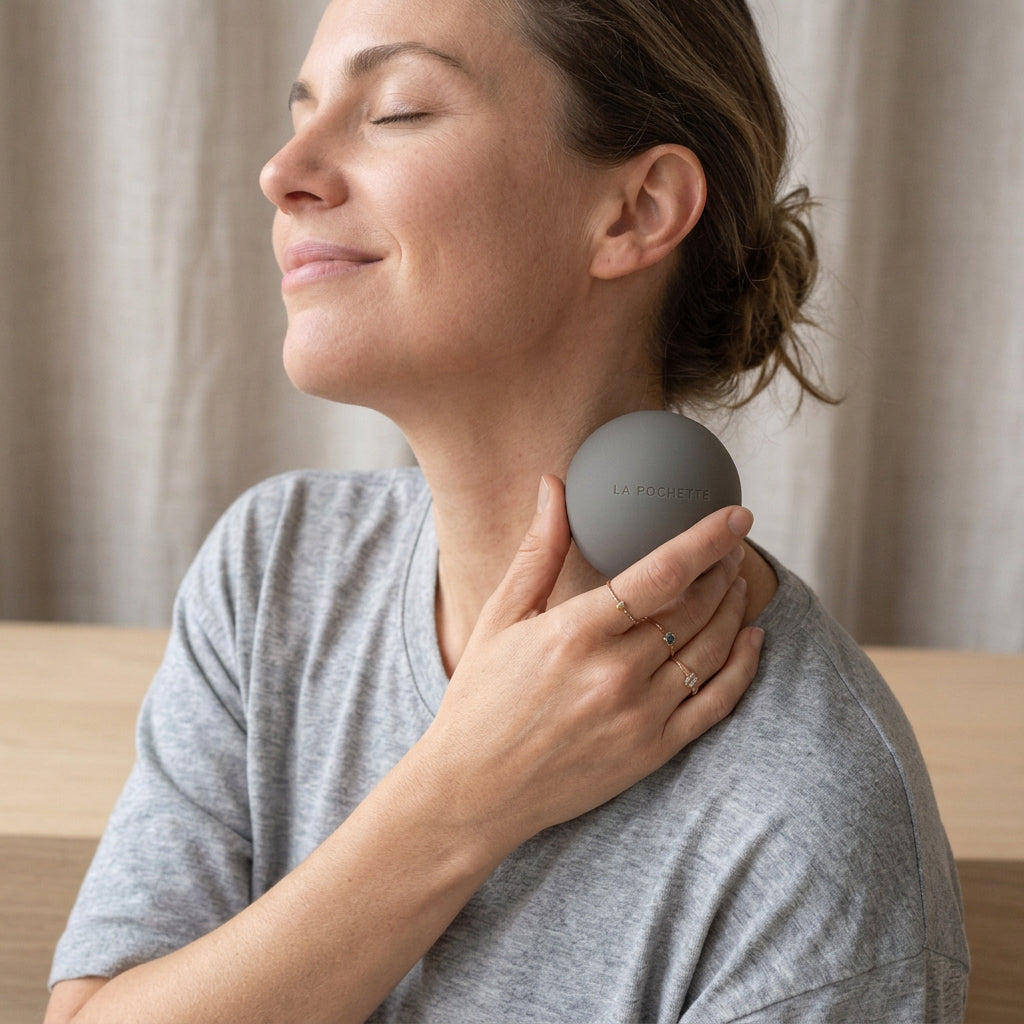 A matte grey silicone recovery ball with the brand name 'LA POCHETTE' embossed on the front, being used as a neck massager