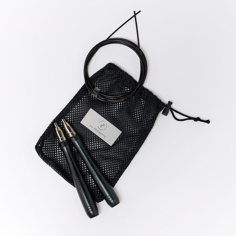 Black La Pochette skipping rope on a black mesh drawstring pouch with a white brand tag, on a clean white background.