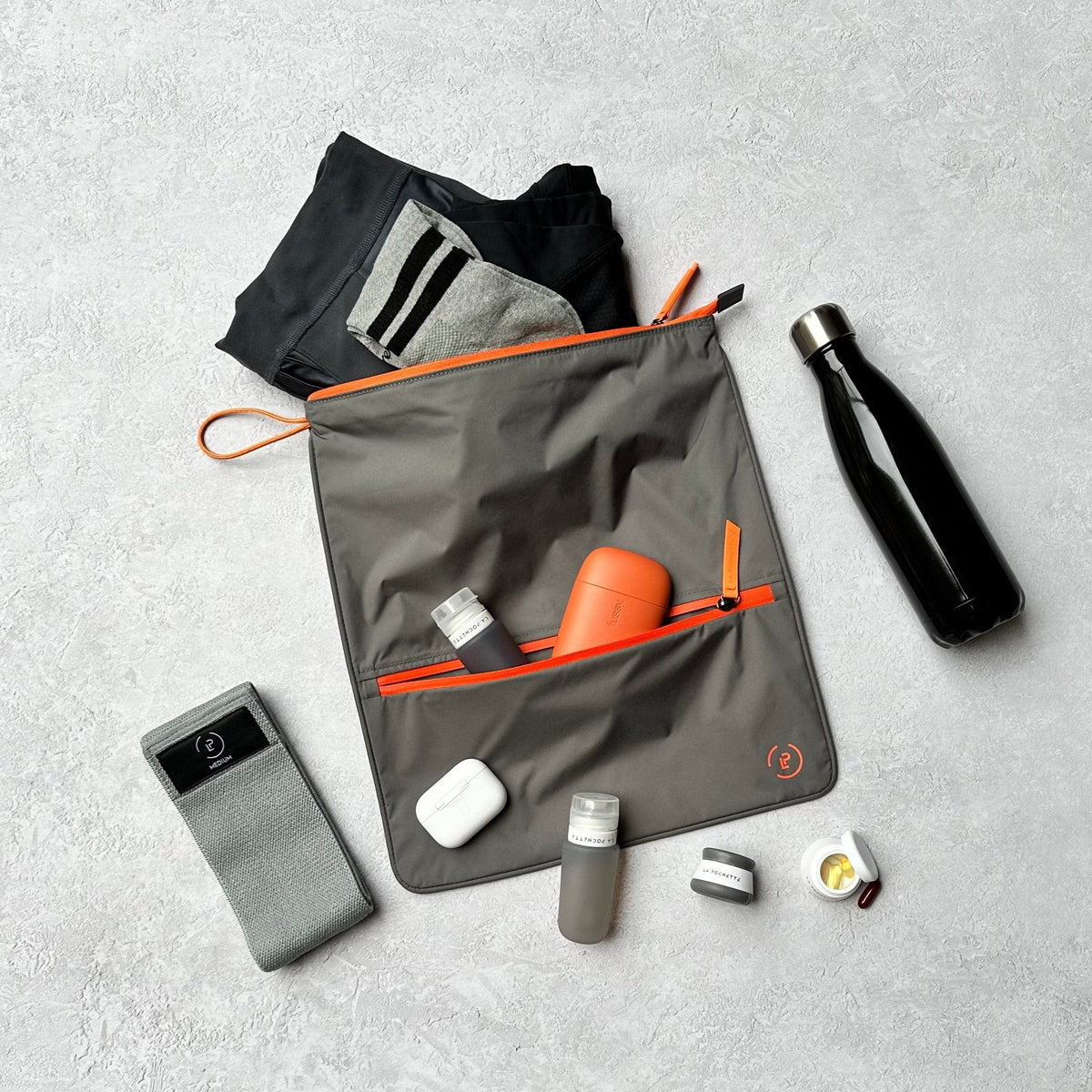 Sweat bag in grey and orange colour with resistance band, travel bottles and water bottle