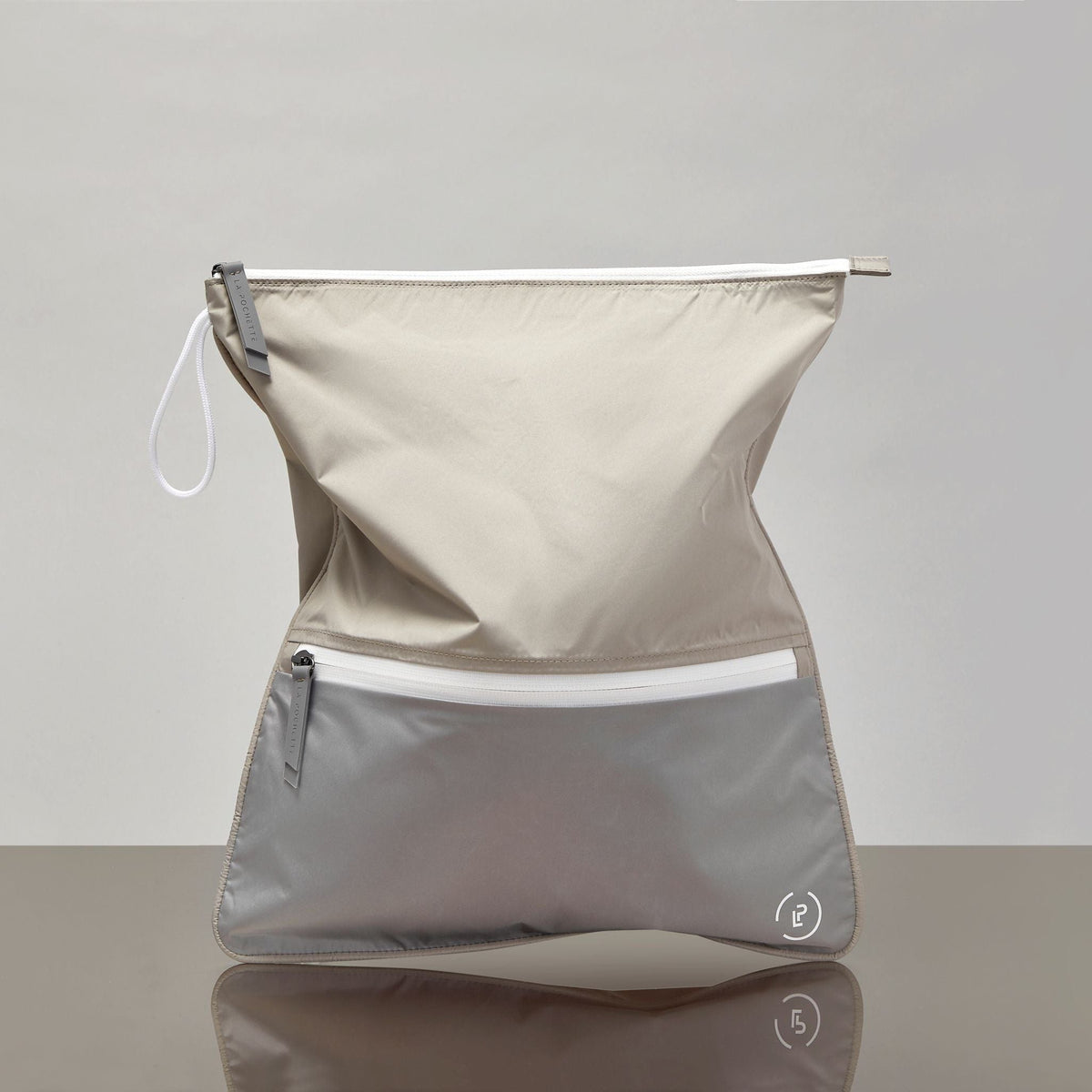 Sweat Bag in soft beige and taupe with shown on a mirrored base.
