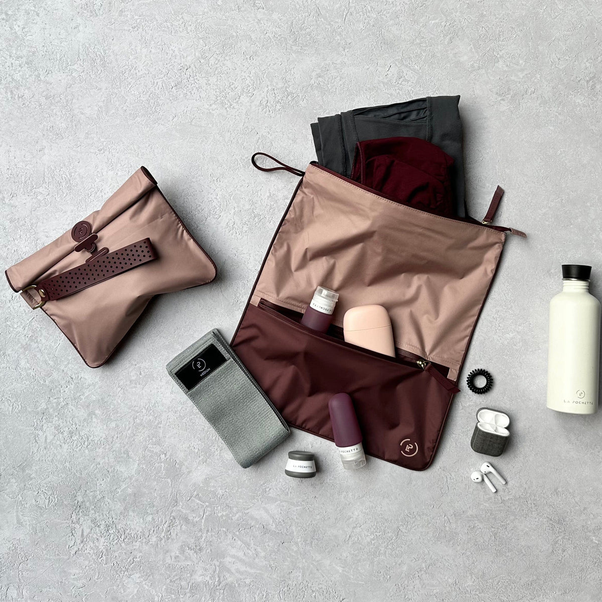 Burgundy and soft pink Sweat Bag styled flat with matching wet bag, travel bottles and other post workout items