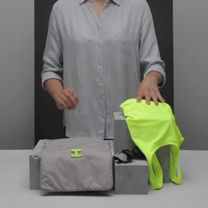 Small Wet Bag in Walnut Neon Green shown being folded up and sunglasses being packed into it 