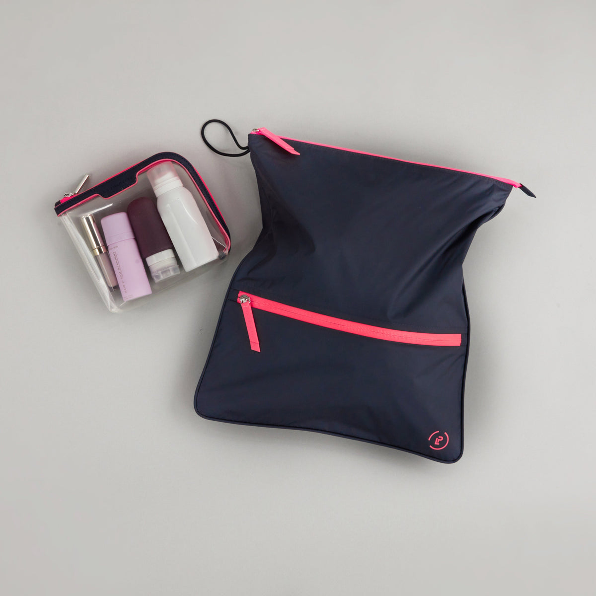 Small Anywhere Everywhere Pouch in Midnight Neon Pink colourway containing beauty accessories next to Sweat Bag in Midnight Neon Pink colourway 