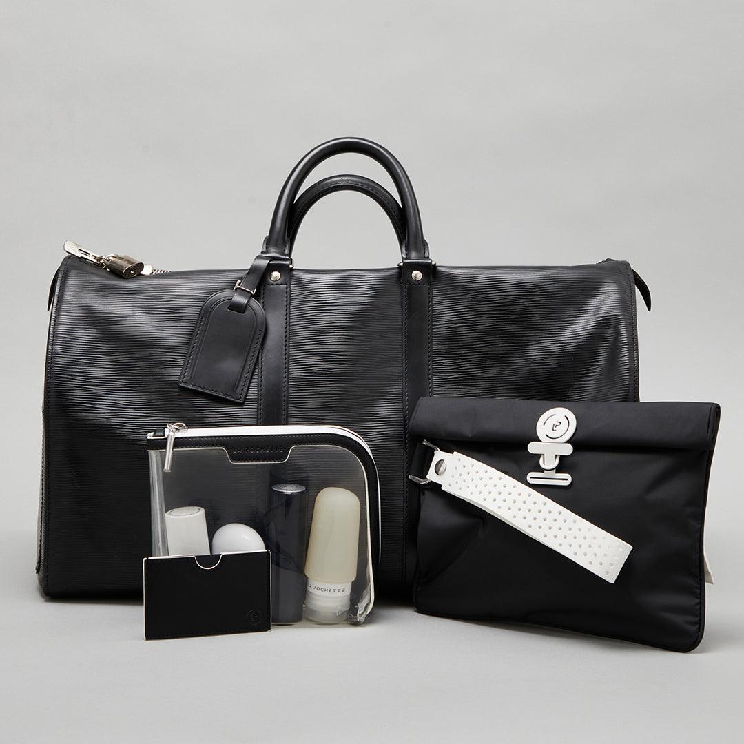 Large Wet Bag in Midnight Ink colourway lying against a leather duffle bag with a small Anywhere Everywhere Pouch containing La Pochette silicone travel bottles
