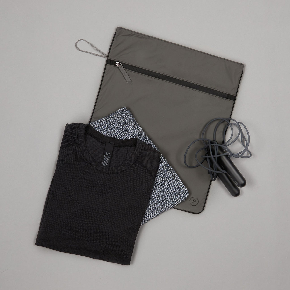 Kit Bag in Pewter Ink colourway with folded gym clothes on top next to Tangram SmartRope 