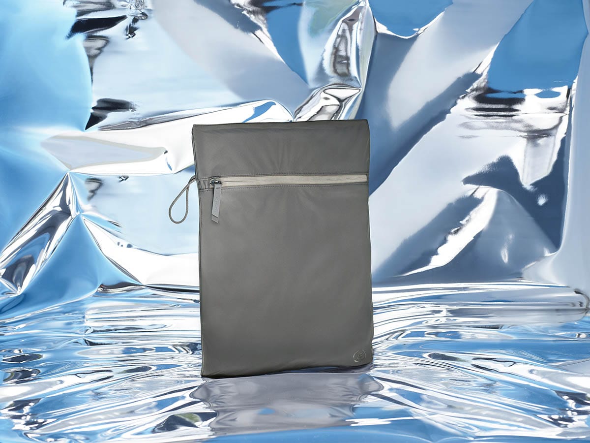 Kit Bag in in dark grey on a blue mirrored abstract backdrop