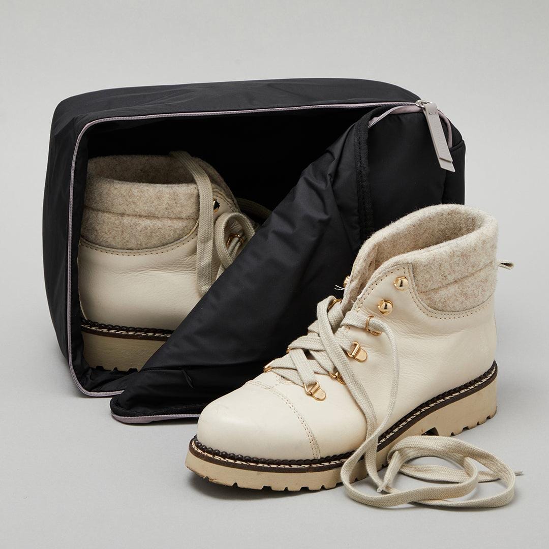 Boots stored inside La Pochette Shoe Bag in black and dark grey